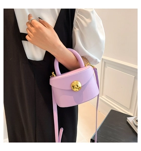 Detail view of light purple leather bag with round gold buckle and slim strap