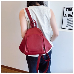 Detail of red lychee grain leather backpack with geometric triangular design on a model