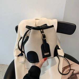 Minimalist canvas bucket bag with black leather trim and vintage gold hardware on a chair