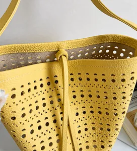 Macro detail of yellow laser-cut leather texture on a bucket bag with smooth drawstrings