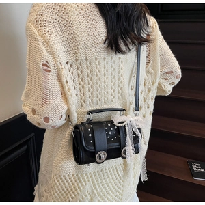 Detail of black leather bag featuring lace bow, pearl chain and rhinestone studs