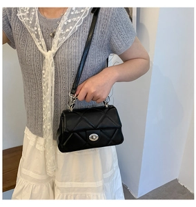 Detail showing classic black quilted crossbody bag with silver turn-lock and chain handle