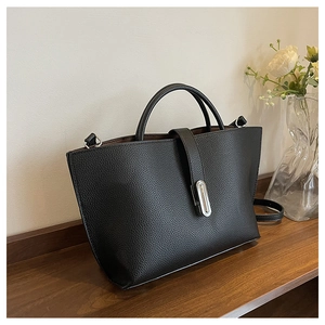 Detailed view of black litchi grain leather tote bag with silver metal oval buckle