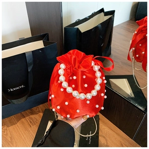 Detail of red satin drawstring bag featuring dense pearl beads and a gold chain strap