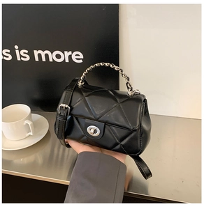 Detailed shot of black quilted crossbody bag featuring a silver twist lock and chain strap
