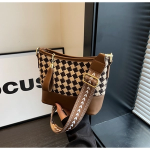 Detail of the brown bucket bag with checkerboard pattern and wide arrow patterned strap