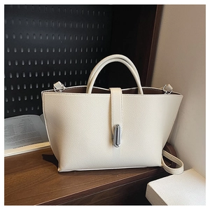 Macro detail of creamy lychee texture leather tote bag with silver metal buckle