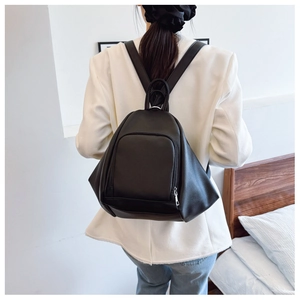 Detail of minimalist black faux leather backpack with pebble texture worn by model