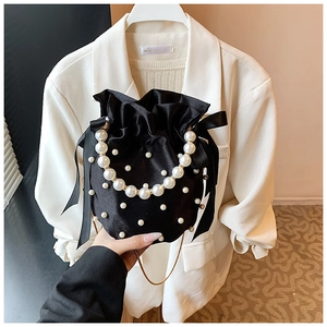 Detail of black satin bucket bag featuring decorative pearls and elegant ribbon bows