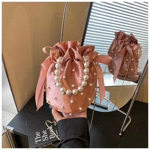 Detail of pink satin bucket bag with pearl handle, drawstring closure, and silk bow