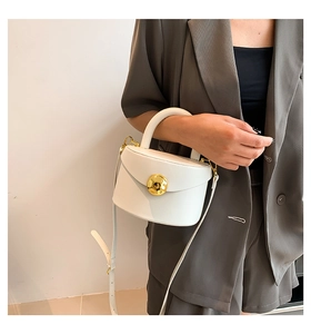 Detail of white leather handbag with round gold metal lock and elegant top handle