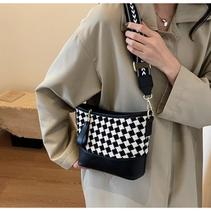 Detail of checkered bucket bag with wide jacquard strap and leather tassel accent