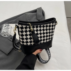 Close-up of houndstooth crossbody bucket bag with gold tassel and geometric strap