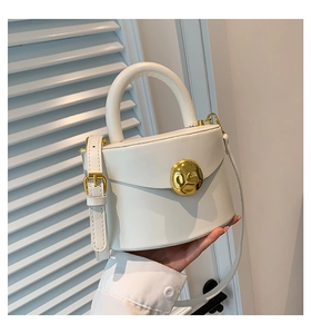 Detail of cream white PU handbag with round top handle and gold metal twist lock