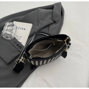 Close-up of black and white geometric bucket bag with wide strap and inner pocket