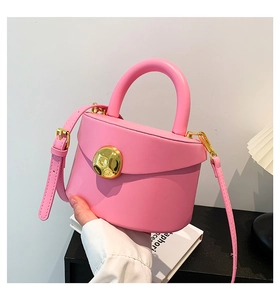 Close-up of pink glossy leather bag with gold round knob buckle and top handle
