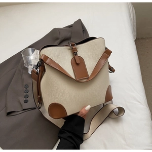 Detail der cremefarbenen Beuteltasche mit Litschi-Leder und breitem gewebtem Schultergurt