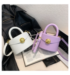 Detail of white and lilac mini bags featuring round gold metal buckles on a magazine