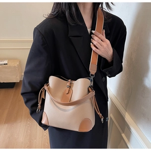Detail der beigen Beuteltasche mit braunem Rand und buntem breitem Textilschultergurt