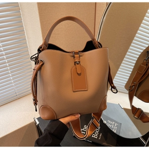 Detail der braunen Beuteltasche mit Litschi-Maserung und breitem gewebtem Schultergurt