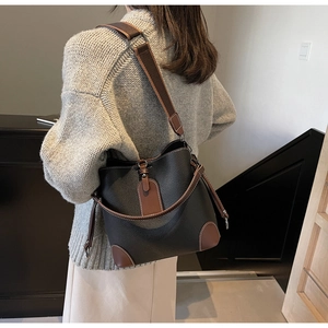Detailansicht einer großen schwarz-braunen Leder-Beuteltasche mit breitem Gurt
