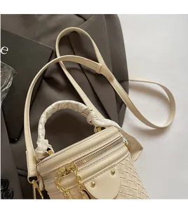 Detail of cream bucket bag with woven texture, floral scarf handle and gold chain strap