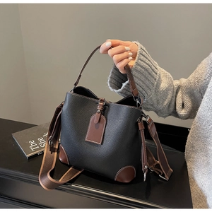 Detail der schwarzen Eimer-Tasche aus strukturiertem Leder mit braunem Besatz