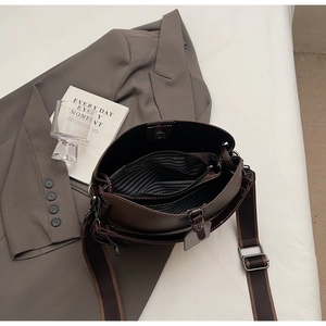 Detail der dunkelbraunen Beuteltasche mit gestreiftem Futter und breitem Schultergurt