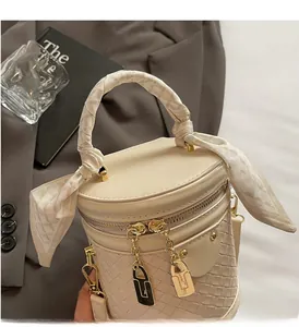 Detail of cream bucket bag with woven texture, silk scarf handle and gold zippers
