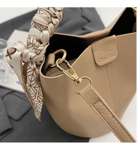 Primo piano della borsa beige in pelle martellata con dettagli dorati e manico in seta