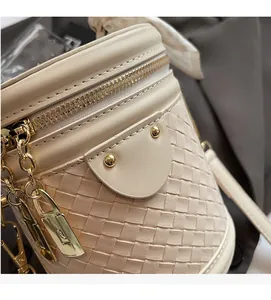 Close-up of cream woven leather texture and gold hardware on fashionable bucket bag