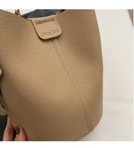 Dettaglio ravvicinato della borsa beige in pelle a grana litchi con cuciture fini