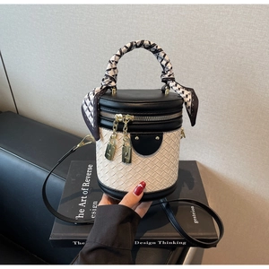 Detail view of contrast bucket bag with woven texture, leather trim and scarf handle