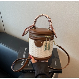 Detail of contrast stitching, silk scarf handle, and metal lock on woven bucket bag