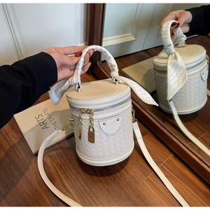Close-up of white bucket bag with woven lattice texture and silk scarf handle detail