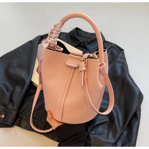 Dettaglio borsa a secchiello rosa in pelle a grana con foulard e finiture dorate