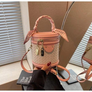 Detail of pink and beige bucket bag featuring woven texture and silk scarf handle