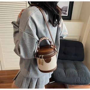 Detail of woven bucket bag with brown leather trim and decorative floral handle scarf