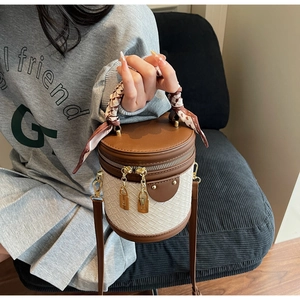 Detail of a brown leather and white weave bucket bag with silk scarf handle and gold rivets