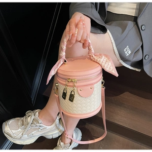 Detail of pink leather bucket bag with quilted texture and silk scarf wrapped handle