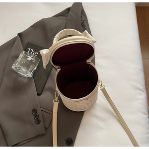 Detail of cream woven bucket bag with wine red lining and decorative silk scarf handle