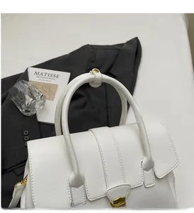 Close-up of white leather handbag featuring a metal buckle and fine stitching details