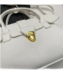 Close-up of a white leather handbag featuring a textured finish and golden twist-lock clasp