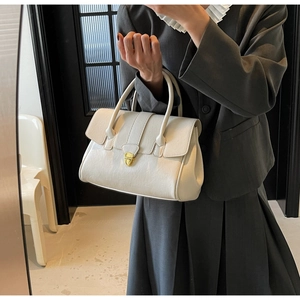 Detail of white vintage-style leather handbag with golden twist-lock and lychee texture