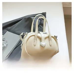 Detail of a creamy beige shell bag with heart leather buckle and silver hardware