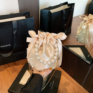 Champagne satin bucket bag with pearls, ribbon bow, and pearl handle for women