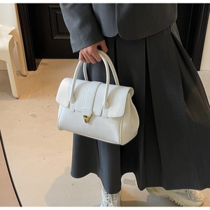 Close-up of white leather handbag with golden shield lock and fine grain texture details