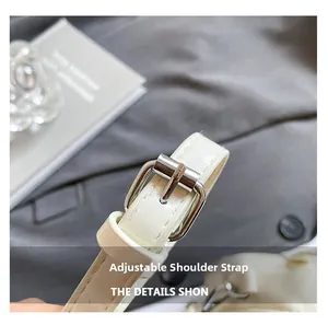 Close-up of adjustable white faux leather shoulder strap with a silver metal buckle