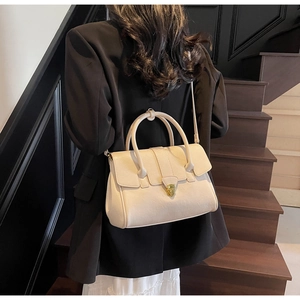 Detail of cream faux leather handbag with golden shield lock and double handles