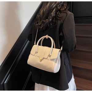 Close-up of stylish cream handbag with gold twist lock and fine leather texture